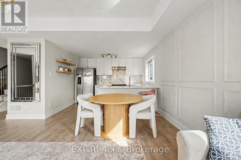 A dining room with a round wooden table and white chairs.
