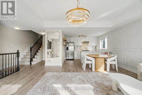 A large, well-lit open space with a dining table and chairs, a staircase, and a chandelier.