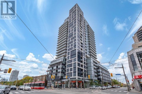 A tall building with many windows is in the center of a busy street.