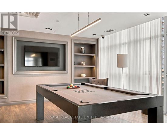 A pool table in a room with a television and shelving units.