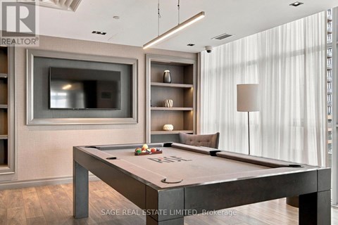 A pool table in a room with a television and shelving units.