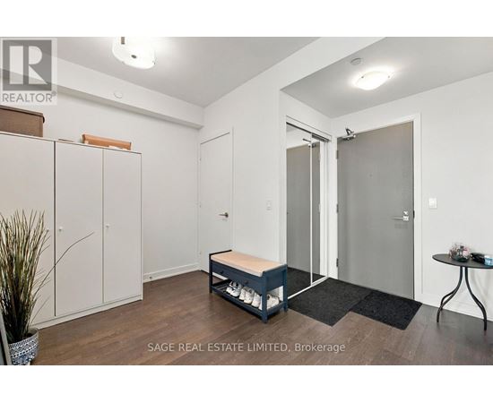 A real estate listing image of a bedroom with a bed, wardrobe, and a small table.