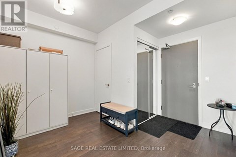 A real estate listing image of a bedroom with a bed, wardrobe, and a small table.