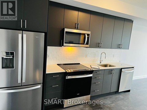 A modern kitchen with a stainless steel refrigerator and a microwave above the stove.