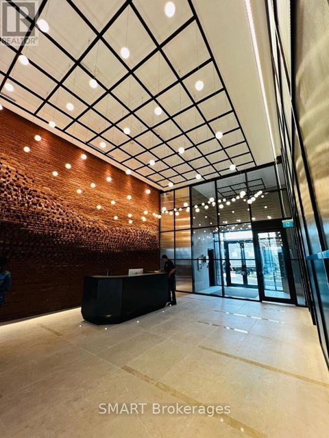 A hallway with a reception desk and people standing by the wall.