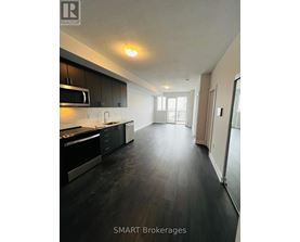 A modern kitchen with black cabinets and a wooden floor.