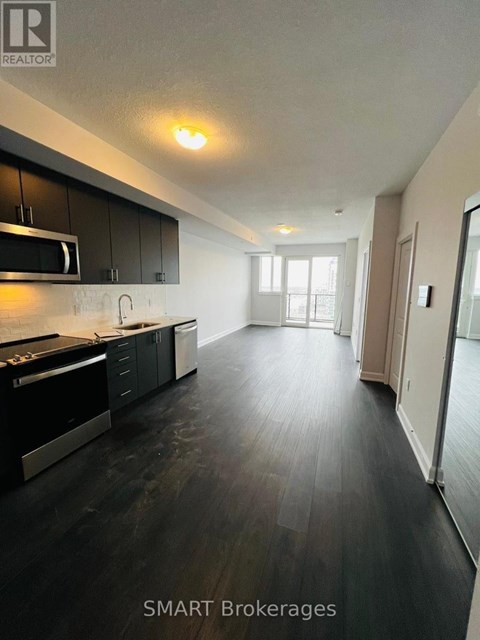 A modern kitchen with black cabinets and a wooden floor.