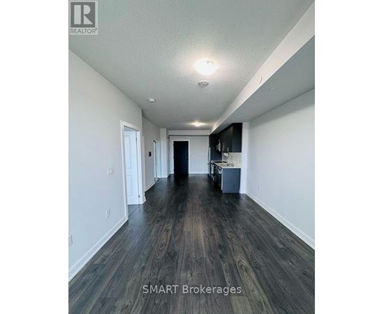 A long hallway with wood floors and white walls.