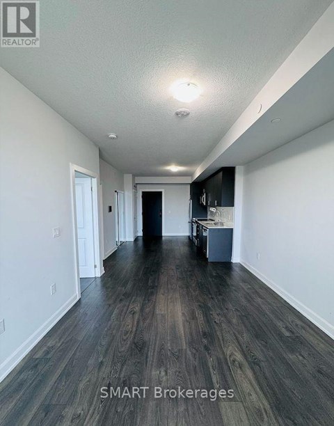 A long hallway with wood floors and white walls.