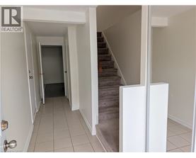 A hallway with a staircase and a door at the end.