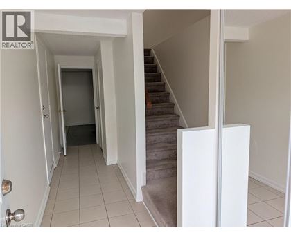 A hallway with a staircase and a door at the end.