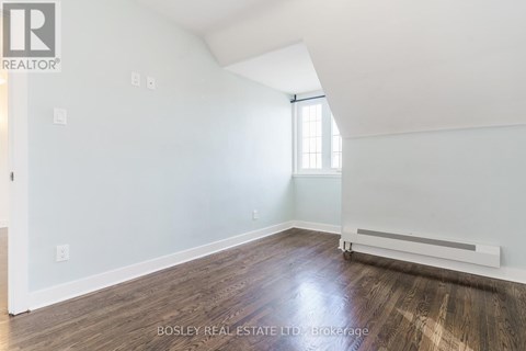 A room with wooden flooring and white walls, with a window on the right side.