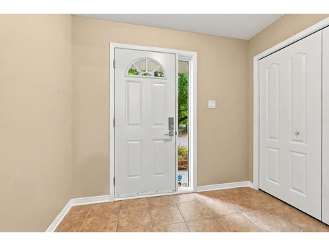 A white door with a glass window is in the middle of a room with tan walls.