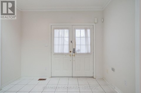A white door with a glass window is in the middle of a white room.