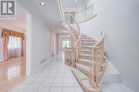 A white hallway with a spiral staircase and a window with curtains.