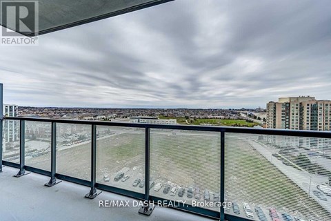 A balcony with a view of a parking lot and buildings.