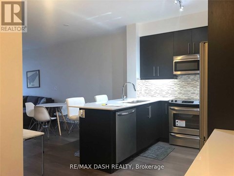 A modern kitchen with black cabinets and stainless steel appliances.