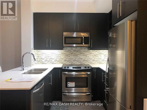 A modern kitchen with black cabinets and stainless steel appliances.