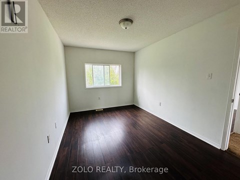 A room with wooden floors and white walls, with a window and a door visible.