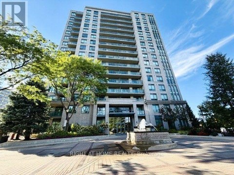 A tall residential building with a fountain in front.