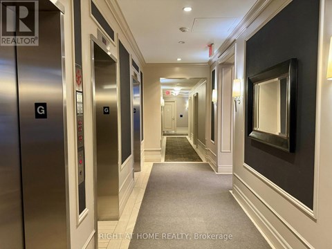 A hallway with elevators on the left and a mirror on the right.