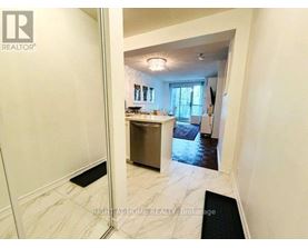 A hallway with a black doormat leading to a kitchen area.