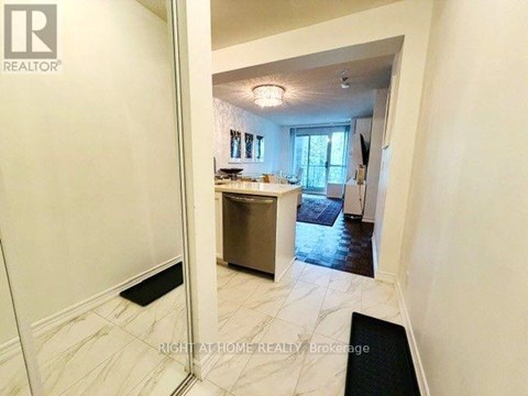 A hallway with a black doormat leading to a kitchen area.