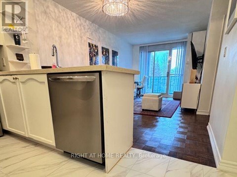 A kitchen with a refrigerator, sink, and a window with curtains.