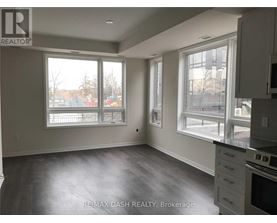 A spacious room with a grey floor and white walls, featuring a kitchen area with a stove and cabinets.