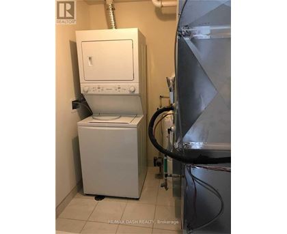 A white dryer is in a small room with a metal wall.