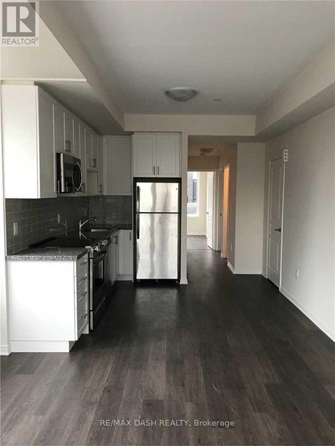 A kitchen with white cabinets and black countertops.
