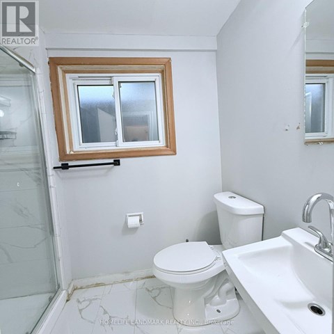 A white toilet sits in a bathroom next to a sink.