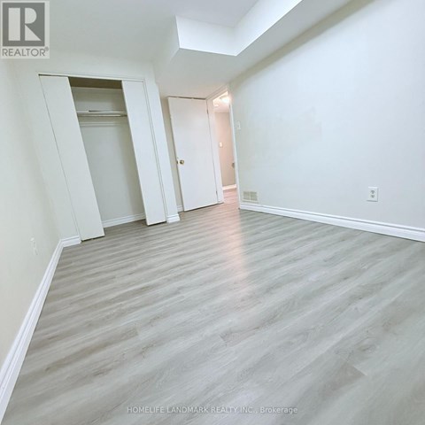 A spacious room with light wood flooring and white walls.