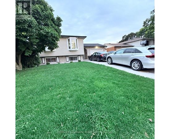 A car is parked on a green lawn in front of a house.