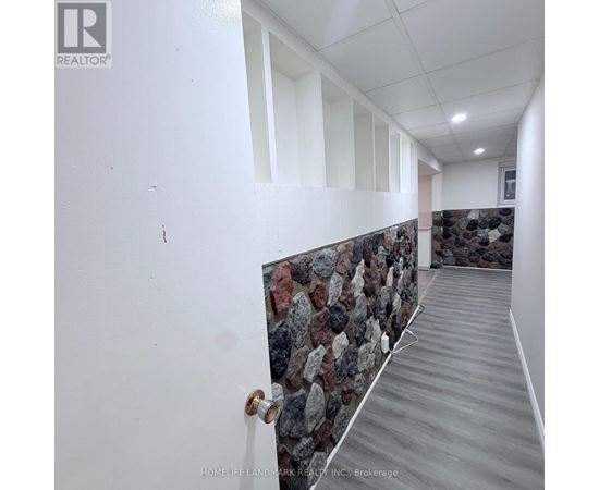 A hallway with a stone wall and wooden floor.