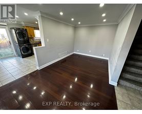 A room with wooden flooring and a staircase on the right side.