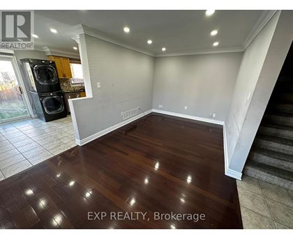 A room with wooden flooring and a staircase on the right side.