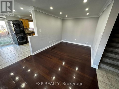 A room with wooden flooring and a staircase on the right side.