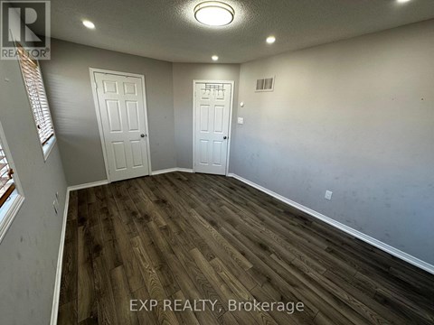 A room with wooden flooring and two white doors.