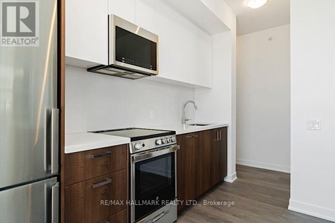 A kitchen with a refrigerator, oven, microwave, and cabinets.