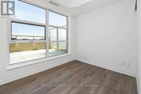 A room with a large window and wooden flooring.
