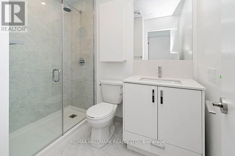 A white bathroom with a toilet, sink, and shower.