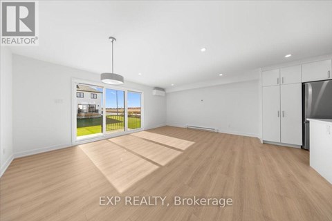 A spacious room with wooden flooring and white walls, with a large window showing an outdoor view.