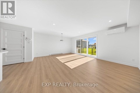 A room with wooden flooring and a large window overlooking a grassy area.