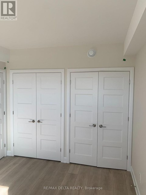 A room with two white doors and a brokerage sign on the wall.