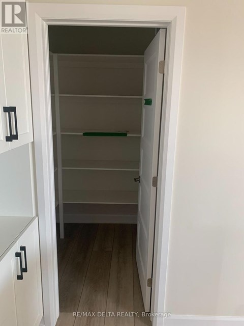 A white pantry with a door open to a hallway.
