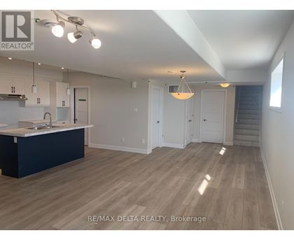 A spacious kitchen with white cabinets and a dark island.