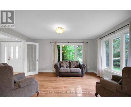 A living room with a couch, chairs, and a window.
