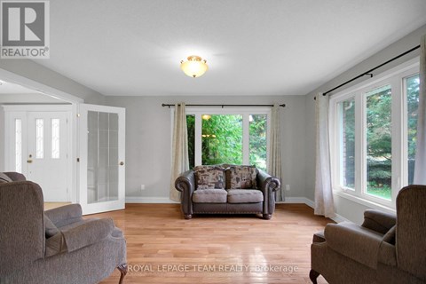 A living room with a couch, chairs, and a window.