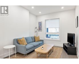 A living room with a grey couch, a white side table, a wooden coffee table, and a flat screen TV.